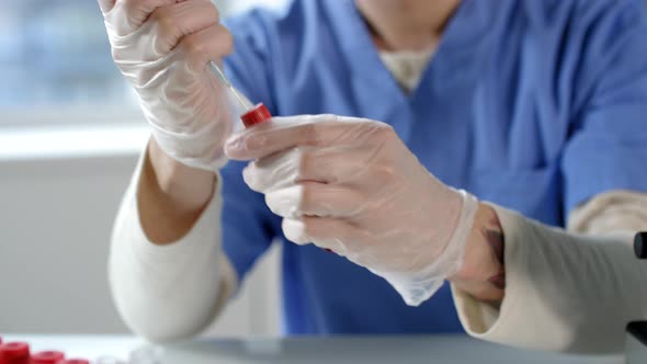 Lab Worker Drawing Blood with Syringe from Test Tube alt