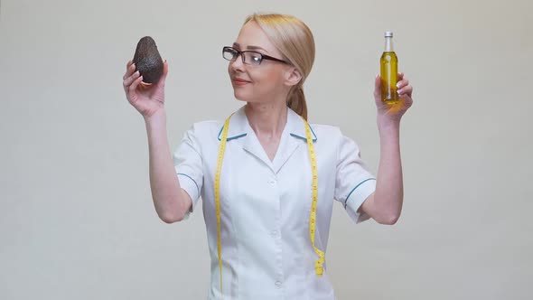 Nutritionist Doctor Holding Organic Avocado Fruit and Bottle of Oil