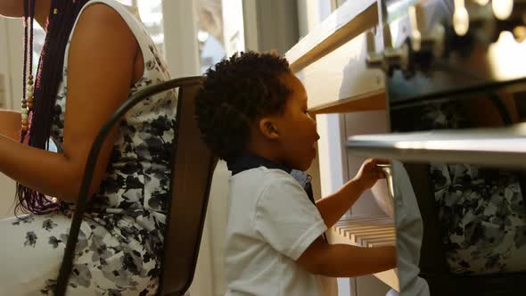 Side view of cute little black son looking in colander in kitchen of comfortable home 4k