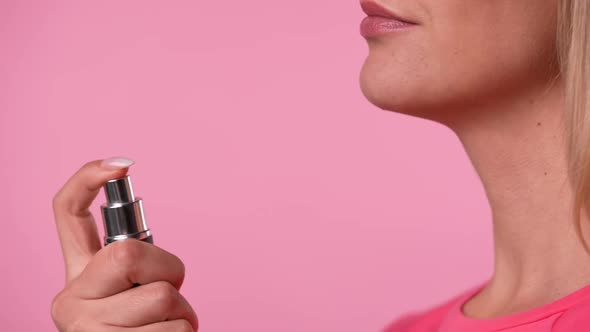 Side View of a Young Blonde Sprinkling Perfume on Herself From Spray Bottle