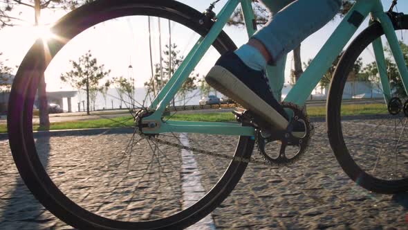 Young Stylish Woman Cyclist Enjoying Fixed Gear Bike Riding Outdoors at Sunrise Near the Sea Close