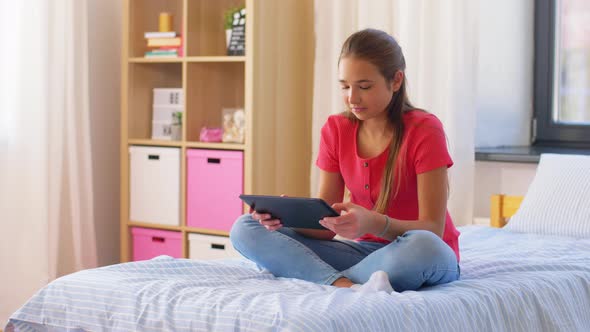 Smiling Girl with Tablet Pc Sitting on Bed at Home