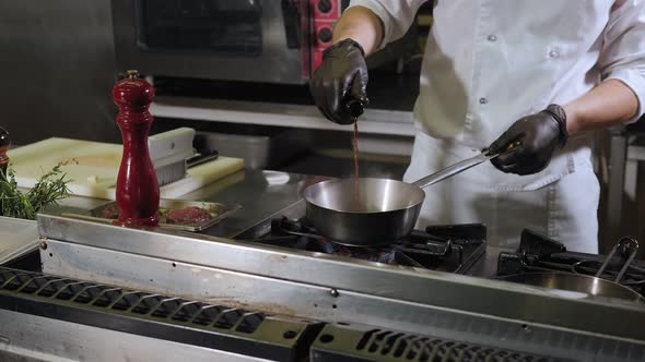 Closeup of the Chef Pouring Red Wine Into a Saucepan in the Restaurant Kitchen