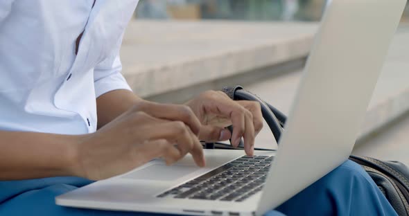 Close Up of Handsome African Businessman Working on Laptop Sitting on Stairs Outdoors