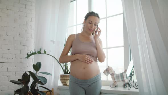 Closeup Cheerful Pregnant Woman Talking Mobile Phone Near Window at Home