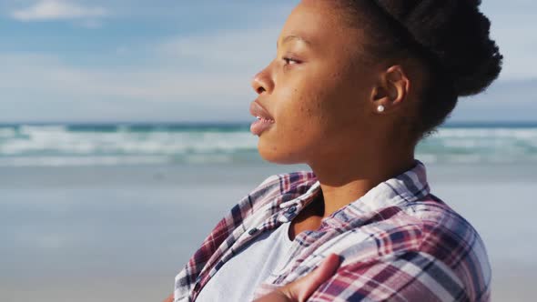 African american woman looking away at the beach on sunny day