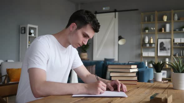 Man Writing on Papers while Sitting on Desk