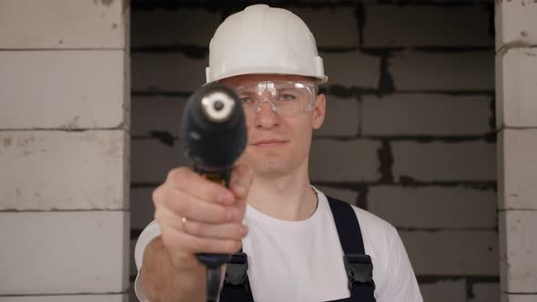 Closeup of a Male Construction Worker Holding a Drill on a Construction Site