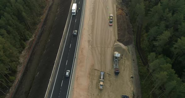 New Highway Road Construction Between Green Forest Aerial View at Sunrise