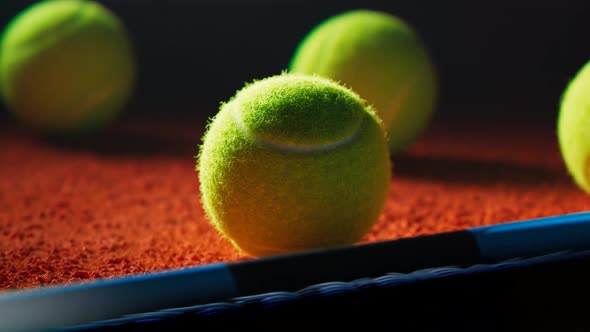 Camera rotating around a tennis ball lying next to racket on the court at night