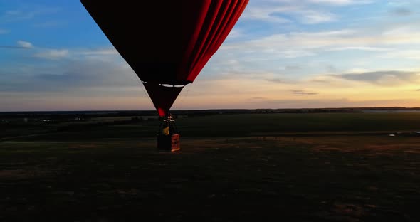 Romantic aerostat at sunset. Hot air balloon in the heart shape with basket travels on beautiful eve