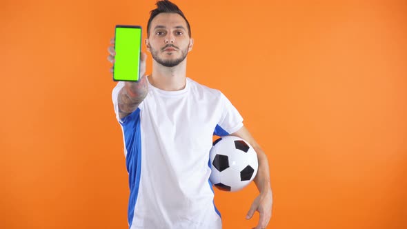 Football Fan In White Blue Shirt Show Green Screen Smartphone Orange Background 