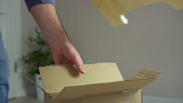 Man Unpacks Cardboard Box Takes Out Pieces of Wooden Furniture