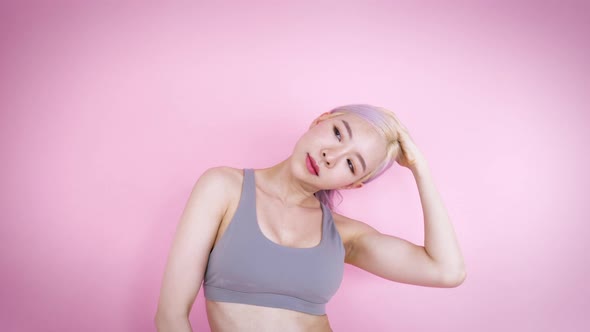 Asian woman muscle stretching exercise workout at home on isolate pink background