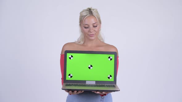 Happy Young Beautiful Blonde Woman Thinking While Showing Laptop