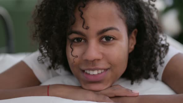 Close Up of African Woman Smiling at Camera in Bed