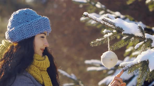 Woman Decorates Fir-tree with Toy During New Year in Forest