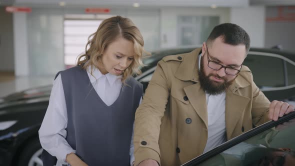 Husband and Wife Choose a New Car in the Showroom of an Official Dealer