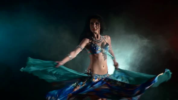 Shiny Torso of a Beautiful Young Girl Belly Dancer on a Black, Blue, Smoke, Back Light