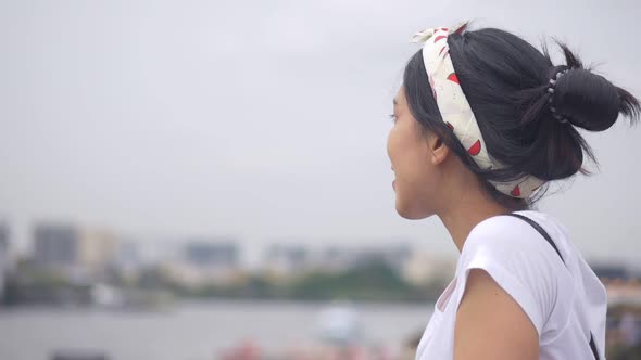 Young Asian woman looking view river at the city and Smile looking at camera.