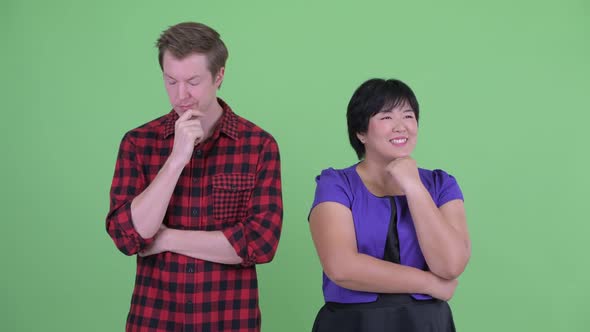 Happy Overweight Asian Woman with Stressed Scandinavian Hipster Man Thinking Together