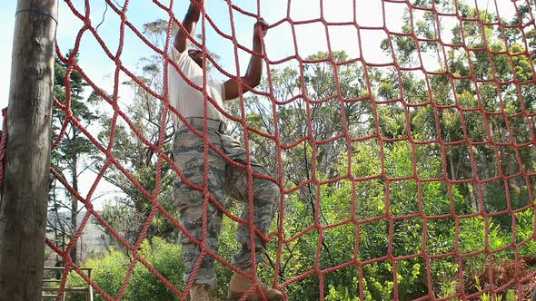 Military soldier climbing rope during obstacle course