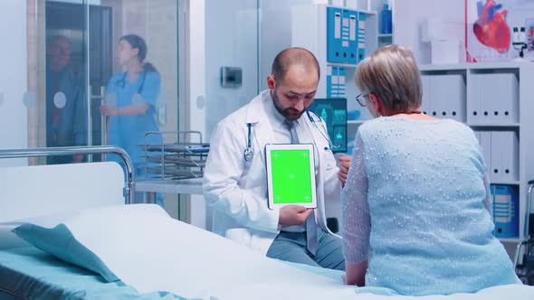 Doctor with Green Screen Tablet in Front of Elderly Patient