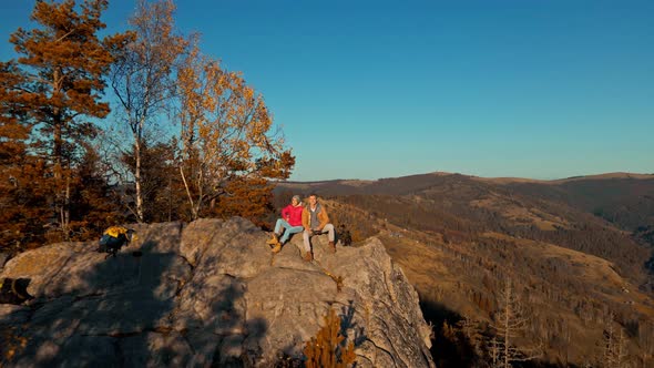 Aerial Drone Selfie Happy Couple Hikers Sitting on Top of Cliff