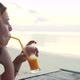 Young Woman Drinking Cocktail on the Beach at Sunset on Background - VideoHive Item for Sale