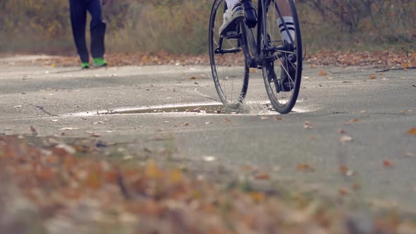 Cyclist Riding On Road Bike. Bike Wheels Rides Through Puddle. Cycling On Puddle And Splashing Water