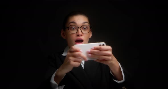 Gambling Business Woman Enthusiastically Plays a Game on a Cell Phone