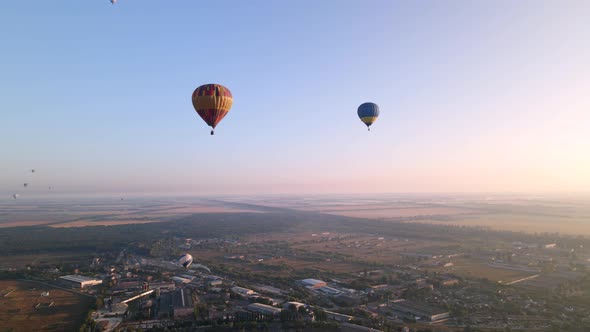 Colorful Hot Air Balloons Flying Over Green Park in Small European City at Summer Sunrise, Aerial