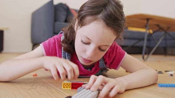 Girl playing and constructing with toy bricks on the living room floor