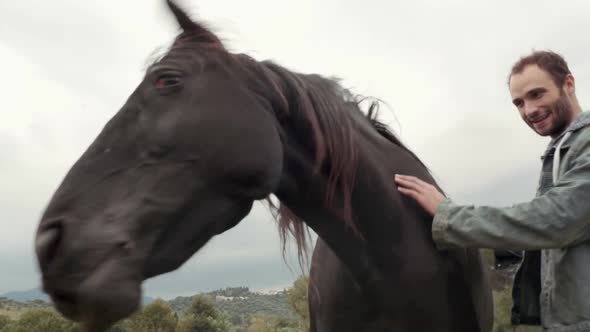 Two Young Friends Man and Woman Smiles Strokes and Hugs Black Horse Outdoor Gimbal Steadicam