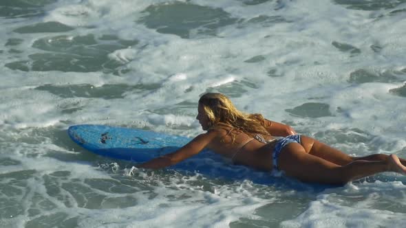 A young woman surfing in a bikini on a longboard surfboard.