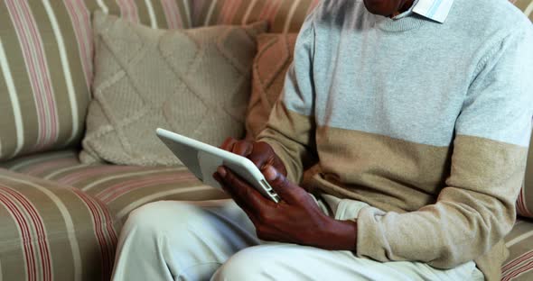 Senior man using digital tablet in living room
