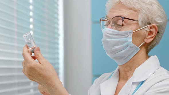 Concentrated lady doctor with protective mask fills syringe