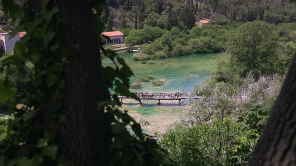 A crowd of tourist gather on a bridge admiring the beautiful waterfalls and turquoise river in Krka