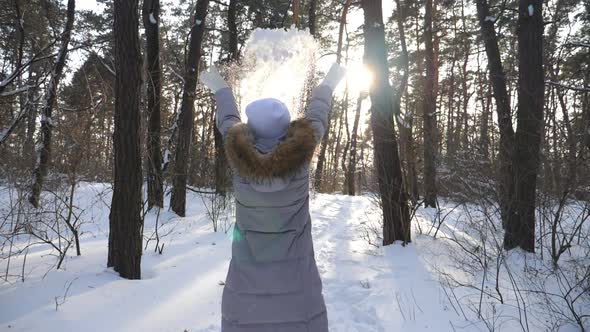 Unrecognizable Woman in Winter Clothes Throwing Handful of Snow