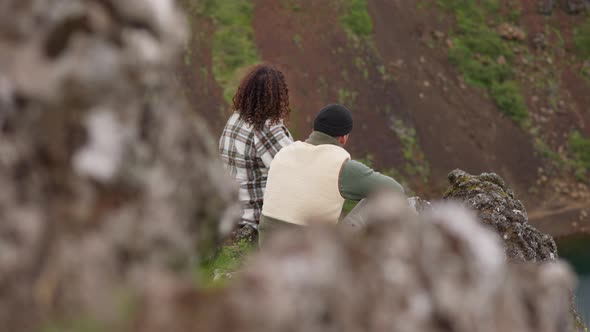 Couple Sitting Together On Rocks Over Lake