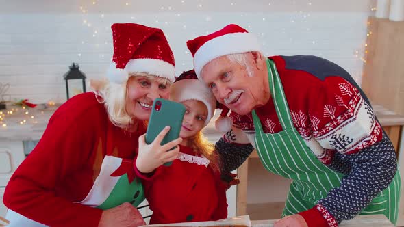 Grandparents Family with Granddaughter Kid Taking Selfie Photo on Mobile Phone at Christmas Kitchen