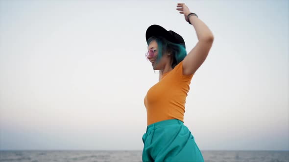 Carefree Unusual Woman with Blue Dyed Hair Dancing, Spinning Around on Sea Background. Femininity
