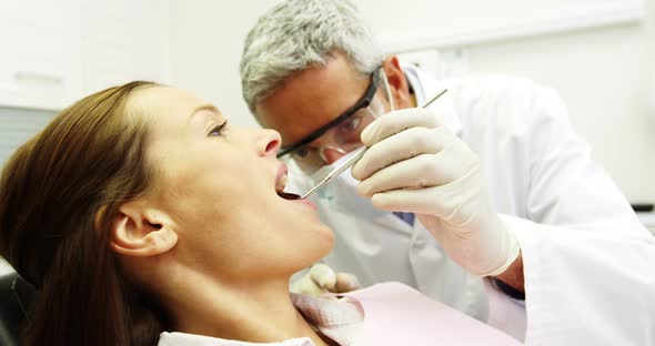 Dentist examining a female patient with tools