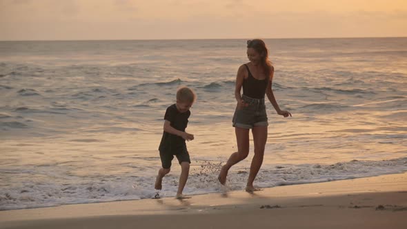 Mother and Son Having Fun on Beach at Sunset