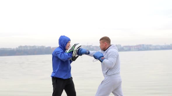 A young fighter in a gray suit runs with dumbbells in his hands and waving his arms