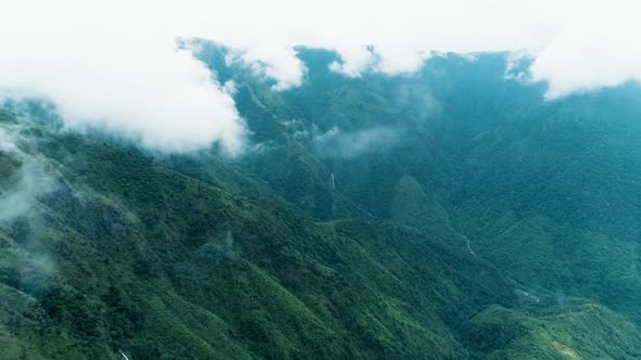 Dramatic panoramic view with green slopes of the mountains covered by big clouds, aerial shot