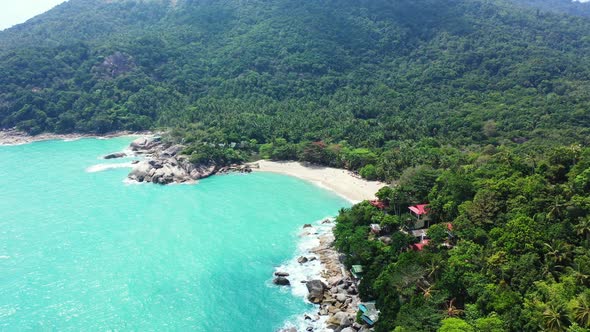 Wide above travel shot of a sandy white paradise beach and blue ocean background in 4K