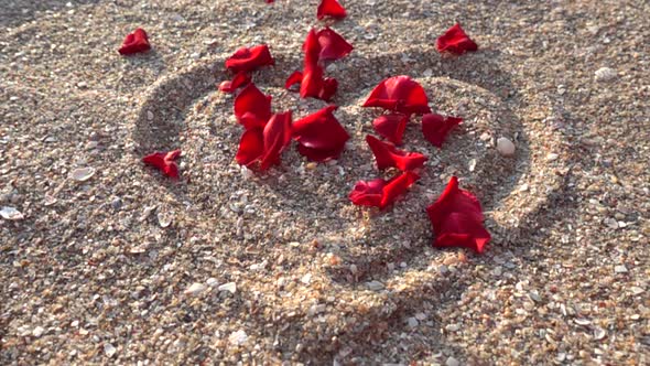 Rose petals in the drawing of a heart on the sand.