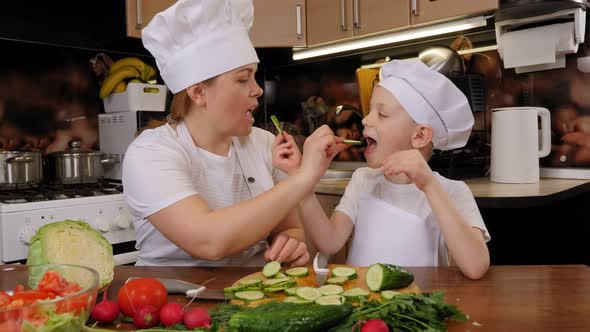 A Mother and Son in an Apron and Caps Cook Vegetables They Eat a Cucumber