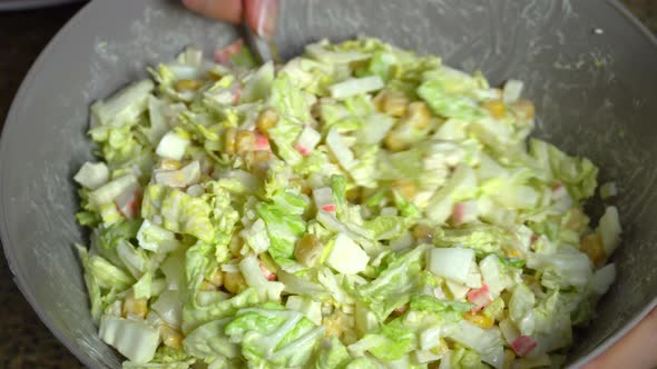 The process of making a vegetarian salad. The cook is stirring the salad.